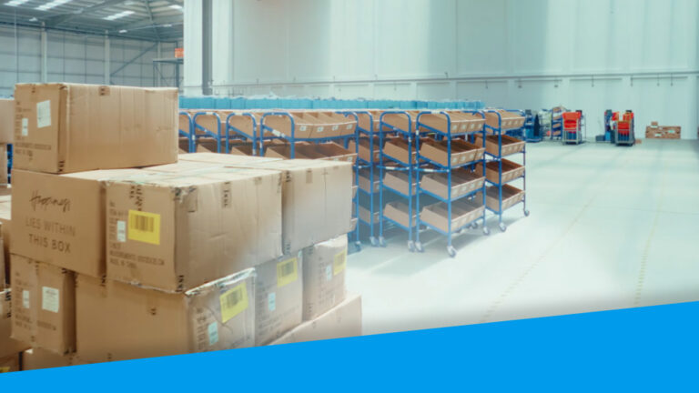 An image from inside a warehouse. It shows order items stacked in the foreground and tidy aisles in the background.