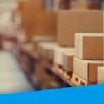 An image showing a warehouse aisle. Boxes are stacked in the foreground.