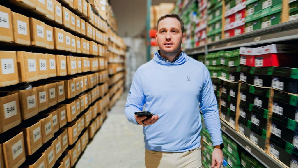 An image showing someone navigating along a warehouse aisle following the instructions of a mobile scanning device.