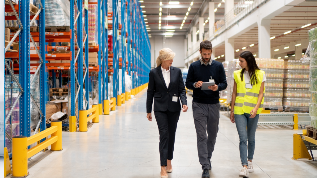 An image of three warehouse workers checking a tablet device as they walk the warehouse floor.