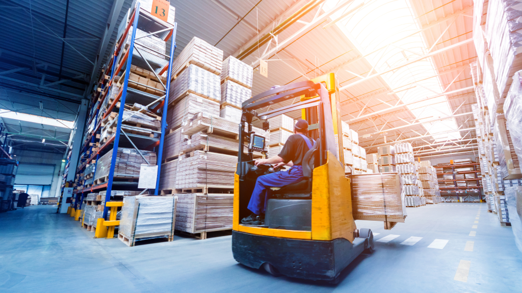 An image showing a warehouse worker using a forklift inside a warehouse.