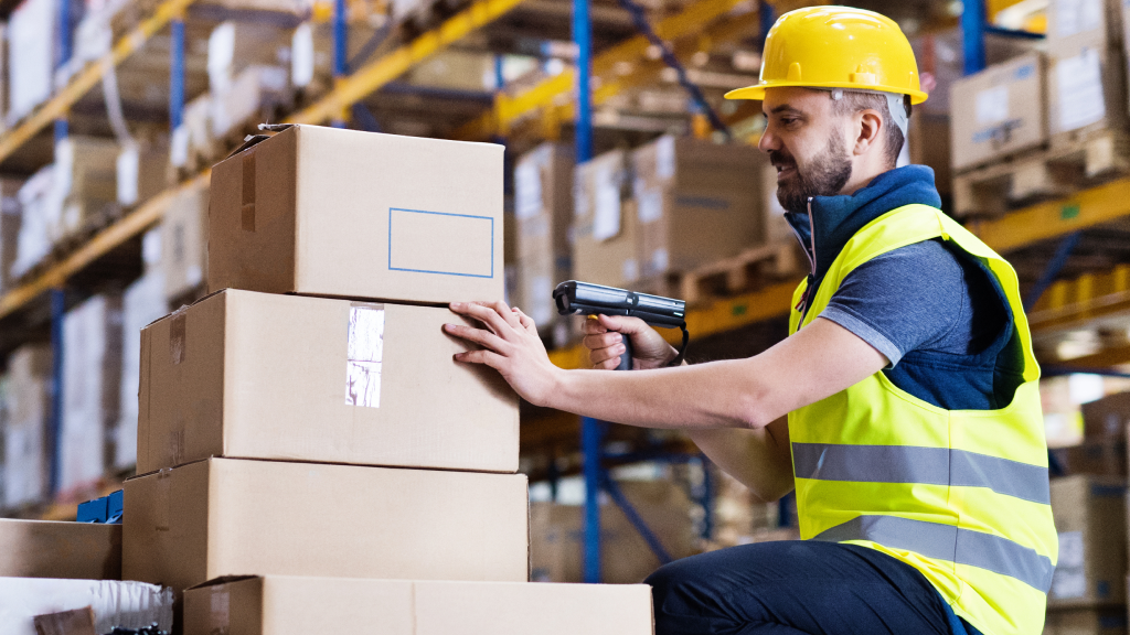A warehouse worker scanning several orders stacked on top of one another with a mobile scanning device.