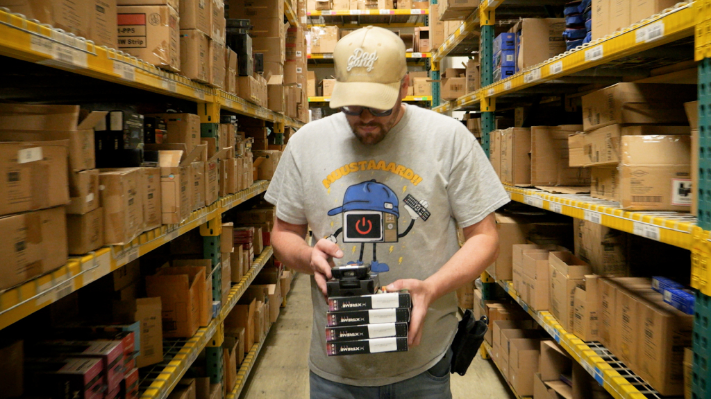 An image showing several order items being picked. The warehouse worker looks down at a mobile device which tells them where to go next.