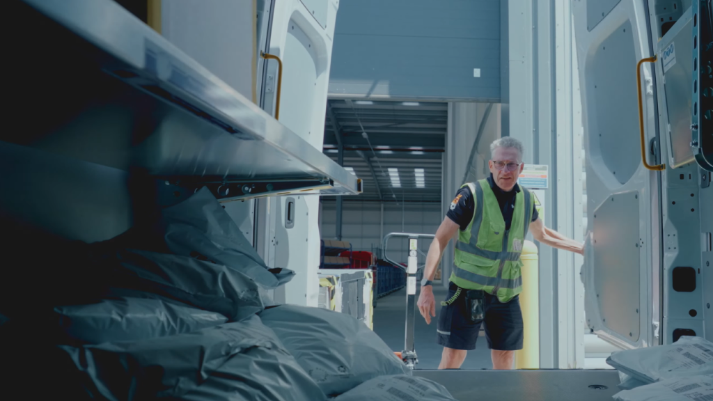 An image showing a courier opening the back of their delivery truck.