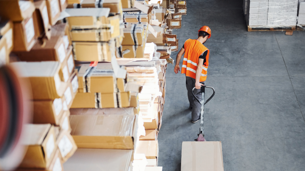 An image of a warehouse worker moving inventory with a hand pallet pump truck.