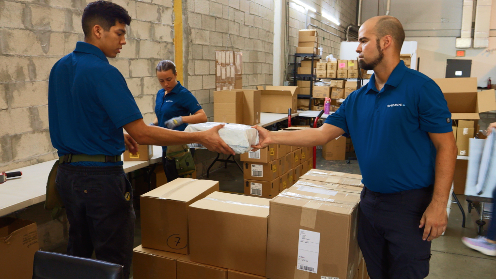 An image showing three warehouse workers preparing orders for shipping.